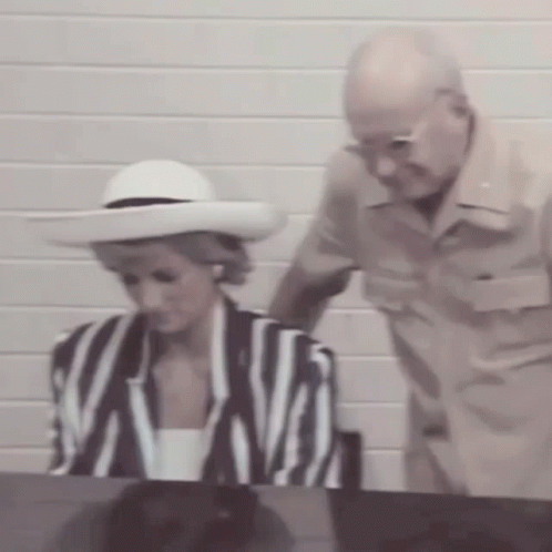 A Man Is Standing Next To A Woman Wearing A White Hat GIF