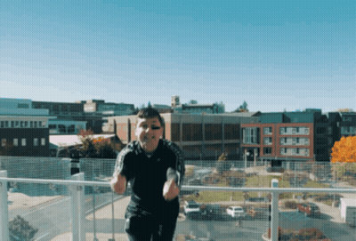 A Man Is Standing On A Balcony In Front Of A City GIF