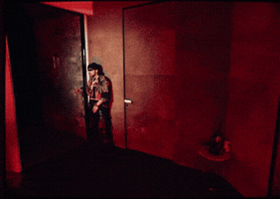 A Man Is Standing On A Balcony Looking Out At The City At Night GIF