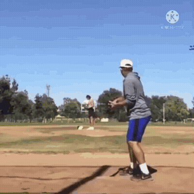 A Man Is Standing On A Baseball Field Holding A Baseball . GIF