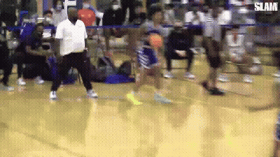 A Man Is Standing On A Basketball Court Watching A Player Shoot A Basketball . GIF