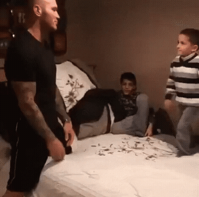 A Man Is Standing On A Bed Next To Two Boys . GIF