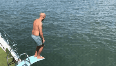 A Man Is Standing On A Diving Board Into The Water GIF