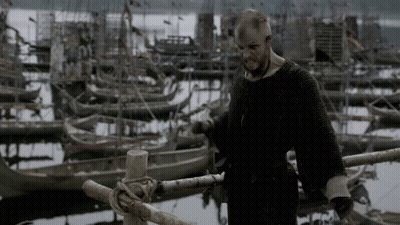 A Man Is Standing On A Dock With Boats In The Background GIF