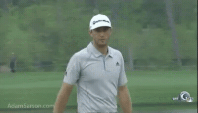 A Man Is Standing On A Golf Course Wearing A Hat And A Polo Shirt . GIF