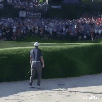 A Man Is Standing On A Golf Course With A Crowd Behind Him And A Sign That Says Travelers On It GIF
