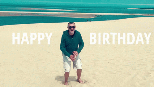 A Man Is Standing On A Sandy Beach With The Words Happy Birthday Behind Him GIF