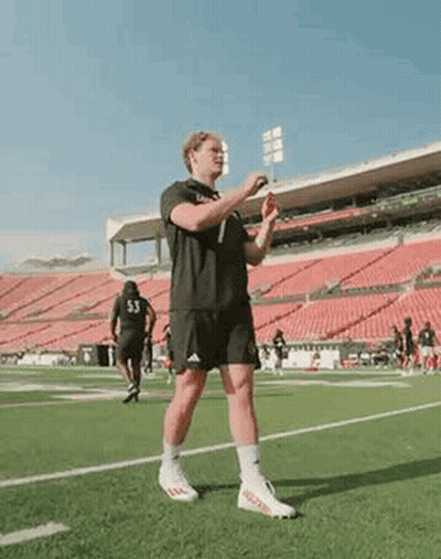 A Man Is Standing On A Soccer Field Holding A Frisbee . GIF