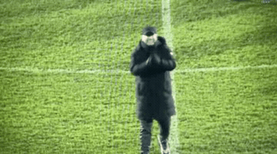 A Man Is Standing On A Soccer Field With His Hands Folded In Front Of Him . GIF