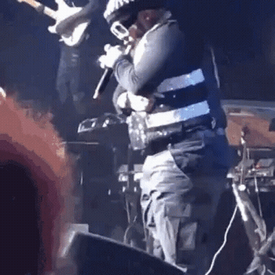 A Man Is Standing On A Stage Holding A Microphone And A Trumpet . GIF