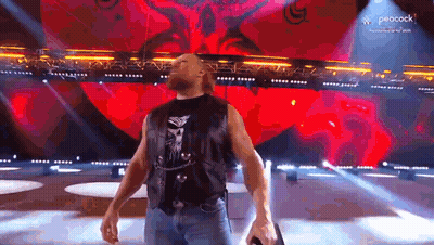 A Man Is Standing On A Stage Holding A Microphone . GIF