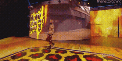 A Man Is Standing On A Stage In Front Of A Large Screen That Says " How You Doin " . GIF