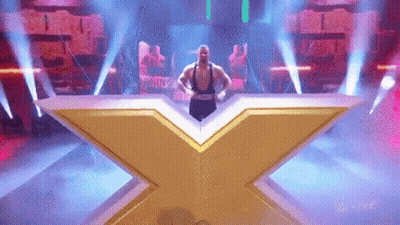 A Man Is Standing On A Stage In Front Of A Large X . GIF