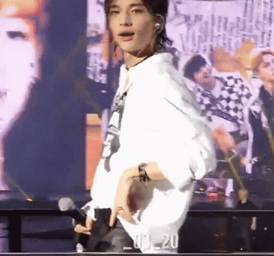 A Man Is Standing On A Stage With A Microphone In His Hand . GIF
