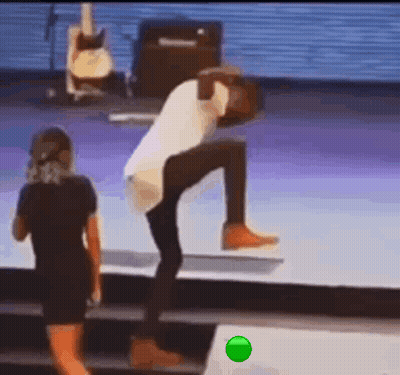 A Man Is Standing On A Stage With His Legs Crossed And A Woman Standing Next To Him . GIF