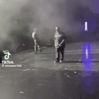 A Man Is Standing On A Stage With Smoke Coming Out Of It And A Tiktok Logo In The Corner . GIF