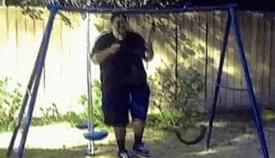 A Man Is Standing On A Swing In A Yard . GIF