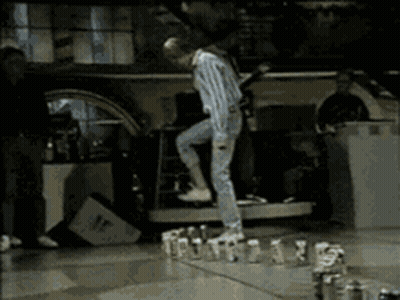 A Man Is Standing On A Table With A Bunch Of Bottles On It GIF