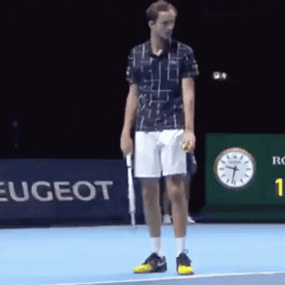 A Man Is Standing On A Tennis Court Holding A Tennis Ball And A Racket . GIF