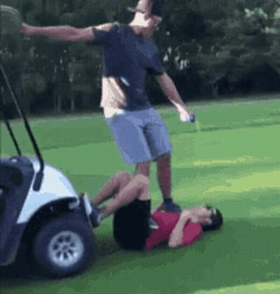 A Man Is Standing On Another Man 'S Back In A Golf Cart On A Golf Course . GIF