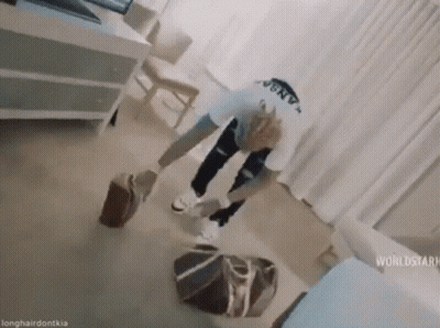 A Man Is Standing On The Floor In A Living Room Holding A Suitcase . GIF