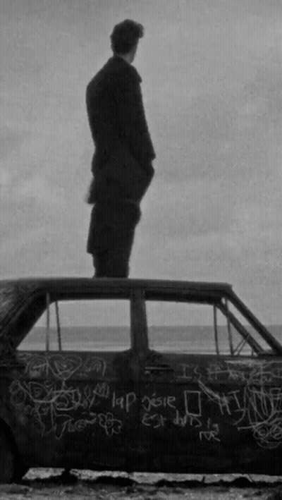 A Man Is Standing On Top Of A Car With Graffiti On It GIF