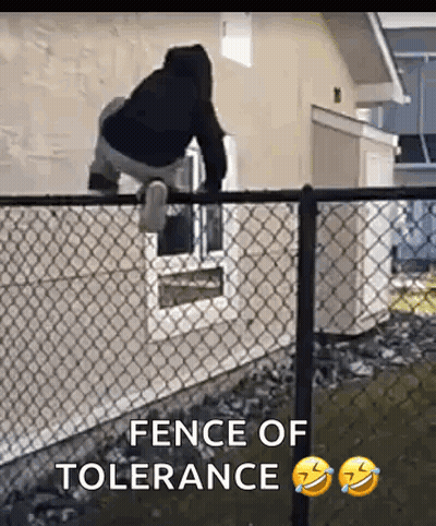 A Man Is Standing On Top Of A Chain Link Fence In Front Of A Window . GIF
