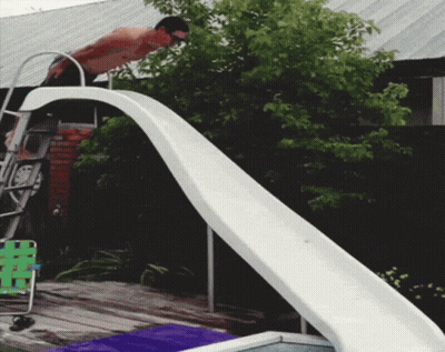A Man Is Standing On Top Of A Slide Looking Down GIF