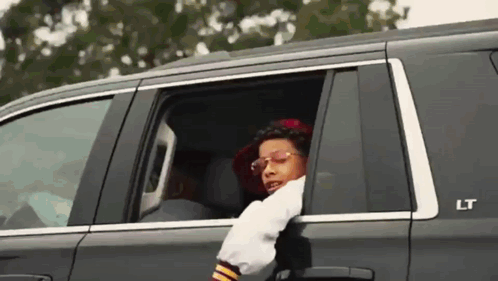 A Man Is Sticking His Head Out Of The Window Of A Car . GIF