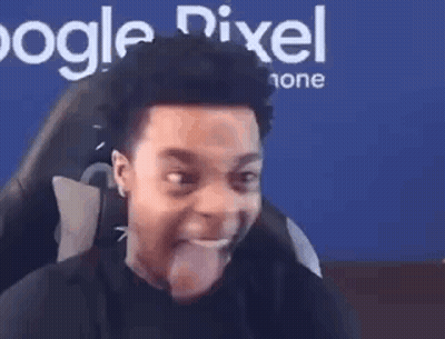 A Man Is Sticking His Tongue Out While Sitting In Front Of A Computer Screen . GIF