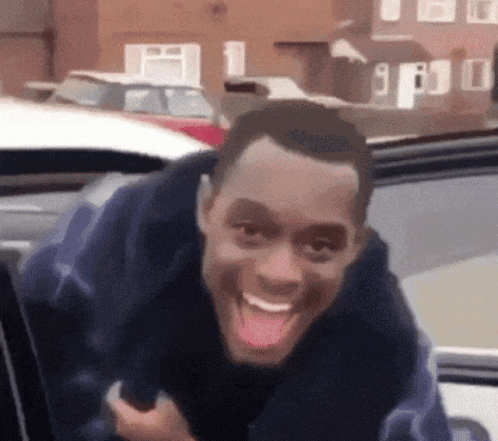 A Man Is Sticking His Tongue Out While Sitting In The Back Seat Of A Car . GIF