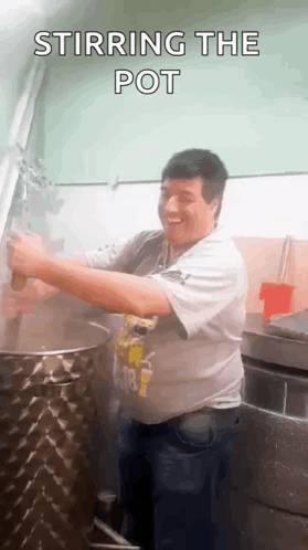 A Man Is Stirring A Pot In A Kitchen With A Spoon . GIF