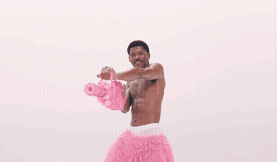 A Man Is Surrounded By Pink Hearts That Are Floating Around Him GIF