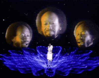 A Man Is Surrounded By Three Heads That Are Projected On To Him GIF