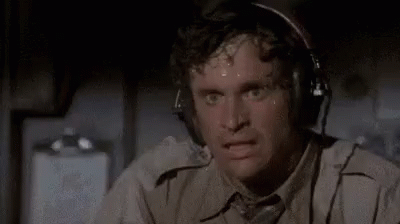 A Man Is Sweating While Wearing Headphones And Looking At The Camera . GIF