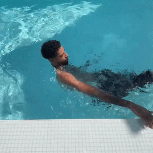 A Man Is Swimming In A Pool With A White Tile Border GIF