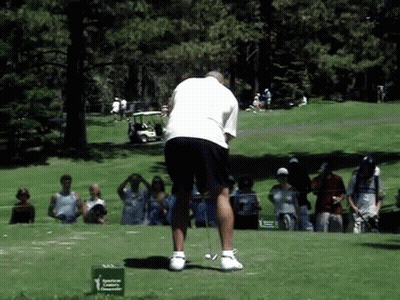A Man Is Swinging A Golf Club On A Golf Course In Front Of A Green Sign That Says American Cancer Society GIF