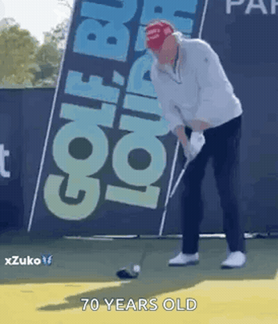 A Man Is Swinging A Golf Club On A Golf Course In Front Of A Sign That Says Golf . GIF