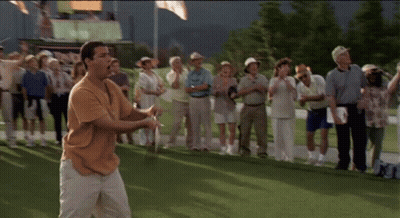 A Man Is Swinging A Golf Club On A Golf Course While A Crowd Watches GIF