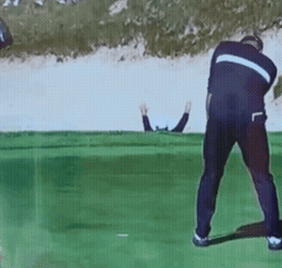 A Man Is Swinging A Golf Club On A Golf Course While Another Man Watches GIF