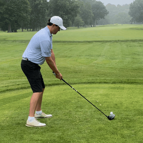A Man Is Swinging A Golf Club On A Green GIF