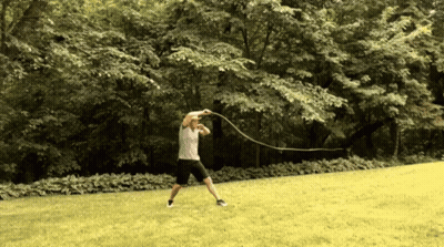 A Man Is Swinging A Rope In A Park GIF