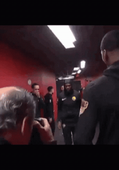 A Man Is Taking A Picture Of A Group Of Men In A Locker Room . GIF