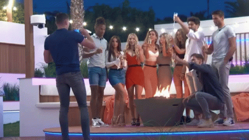 A Man Is Taking A Picture Of A Group Of People Holding Champagne Glasses GIF