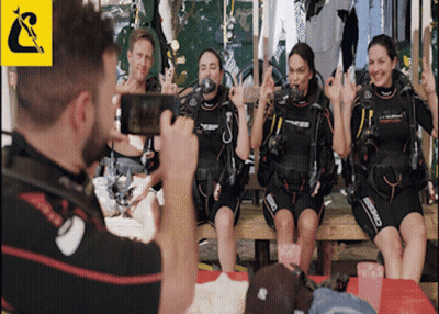 A Man Is Taking A Picture Of A Group Of Scuba Divers Wearing Cressi Wet Suits GIF