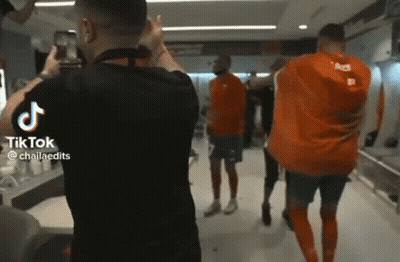 A Man Is Taking A Picture Of A Group Of Soccer Players In A Dressing Room . GIF