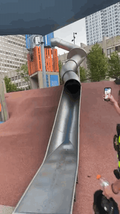A Man Is Taking A Picture Of A Slide At A Playground GIF