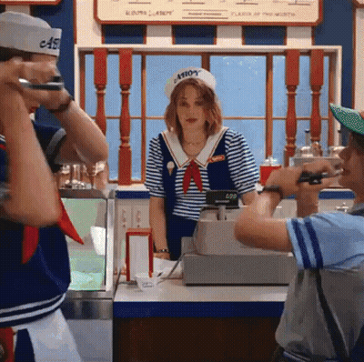 A Man Is Taking A Picture Of A Woman In A Sailor Costume At An Ice Cream Parlor . GIF