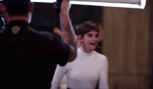 A Man Is Taking A Picture Of A Woman In A White Sweater GIF