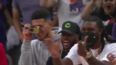 A Man Is Taking A Picture Of Another Man With A Camera While Sitting In The Stands . GIF